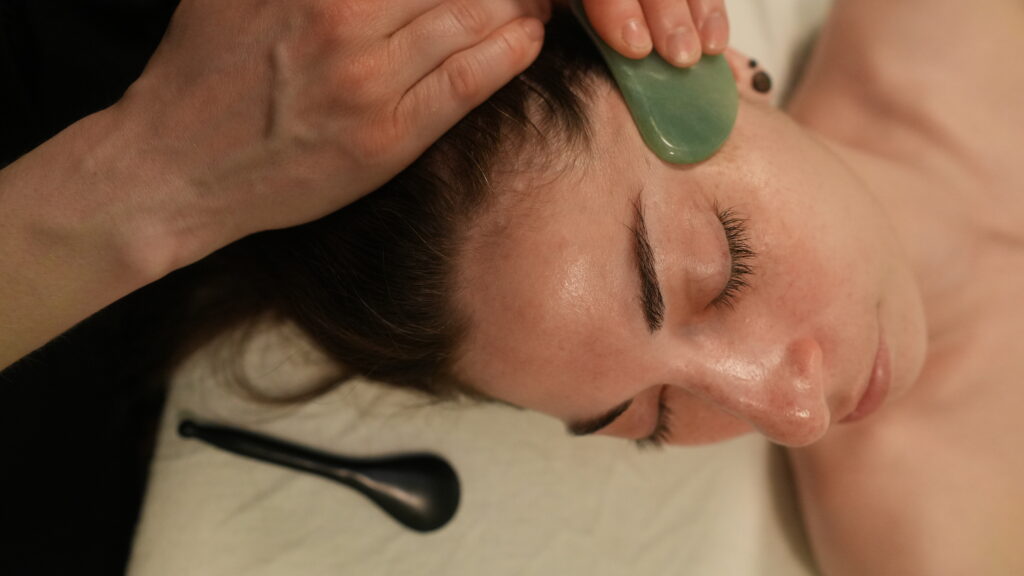 Cosmetic Acupuncture 1 A facial guasha treatment using a jade guasha tool, which is often used during a Cosmetic Acupuncture treatment at Peony Tree Medicine.